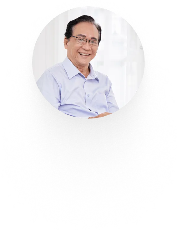 Ảnh tròn cắt nền: người đàn ông lớn tuổi đeo kính, áo sơ mi xanh nhạt, khoanh tay cười hiền bên khung cửa sổ sáng — ô thứ nhất dải ảnh học viên
