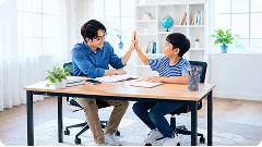 Thầy giáo và nam sinh đập tay ăn mừng qua bàn học có sách vở và máy tính bảng trong phòng nhiều ánh sáng — ảnh thẻ hỗ trợ Lớp học live