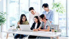 Năm bạn trẻ quây quanh một chiếc laptop trên bàn, cùng nhìn màn hình và cười — ảnh thẻ hỗ trợ Lớp học video